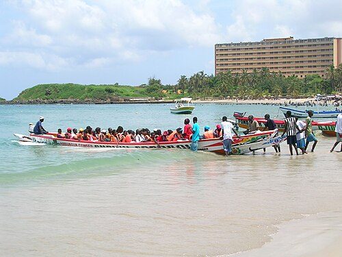 Visitors loaded into a Pirogue for a pleasure trip from Ngor to île de Ngor, a popular holiday spot for Dakar's locals. In the background is the Ngor Hotel, catering to Senegalese and business travelers to Dakar.