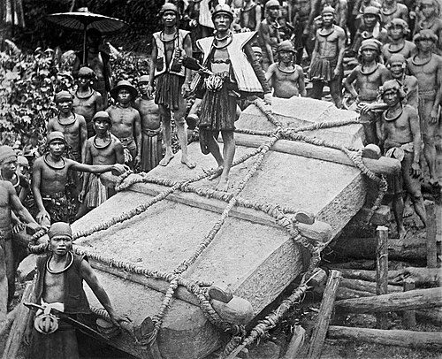 Nias men carrying a stone for construction for the deceased ruler Saunigeho of Bawömataluo around 1915.