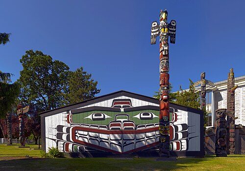 Wawadit'la, a Kwakwakaʼwakw "big house", with a totem pole in Thunderbird Park