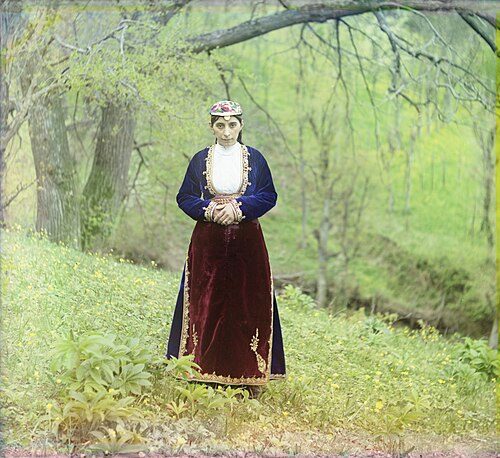 An Armenian woman in national costume poses on a hillside near Artvin, circa 1910.
